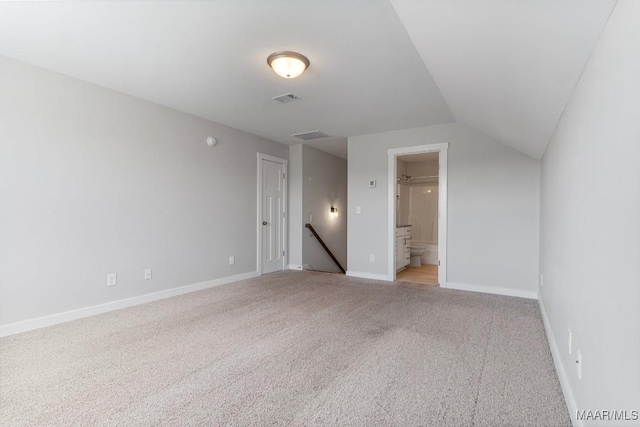 empty room featuring light colored carpet and vaulted ceiling