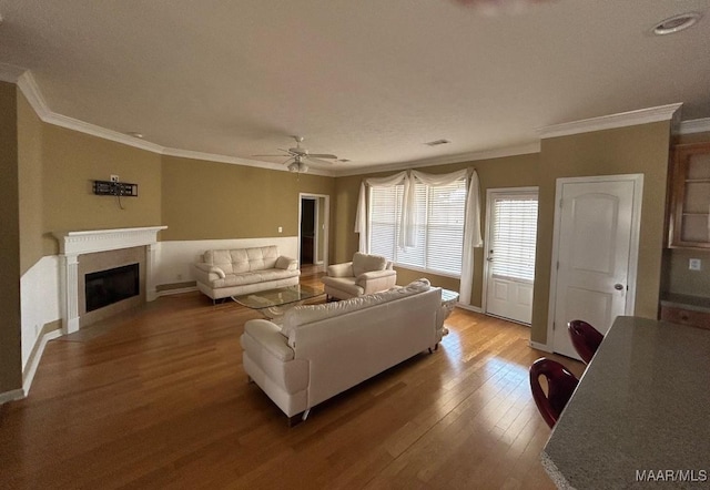 living room with ceiling fan, ornamental molding, and wood-type flooring