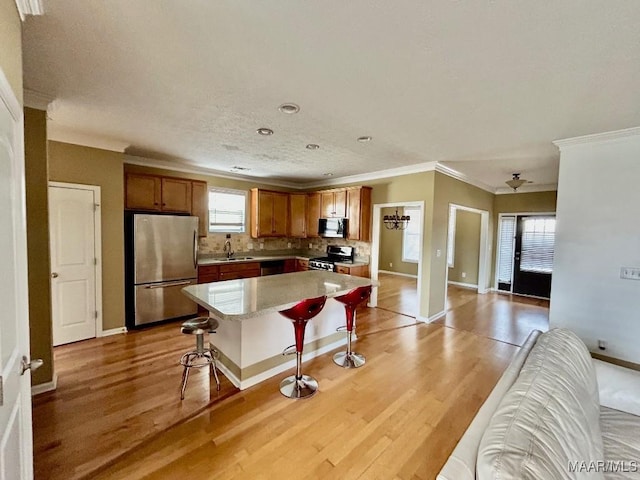 kitchen featuring light hardwood / wood-style flooring, a breakfast bar, backsplash, stainless steel appliances, and a center island