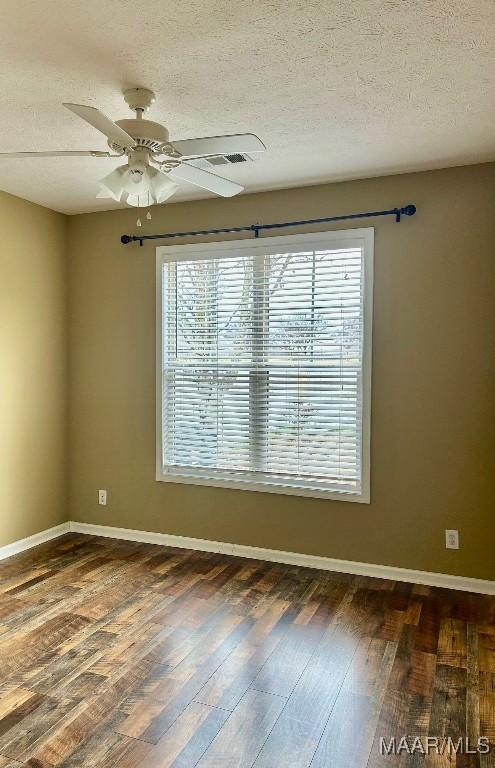 unfurnished room with ceiling fan, dark hardwood / wood-style flooring, and a textured ceiling