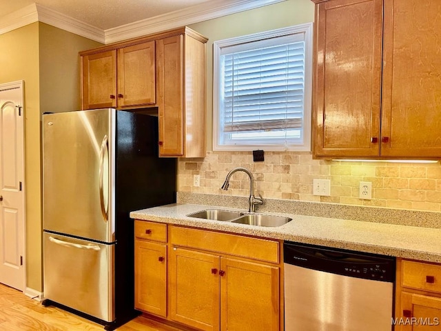 kitchen featuring sink, crown molding, light hardwood / wood-style flooring, appliances with stainless steel finishes, and tasteful backsplash