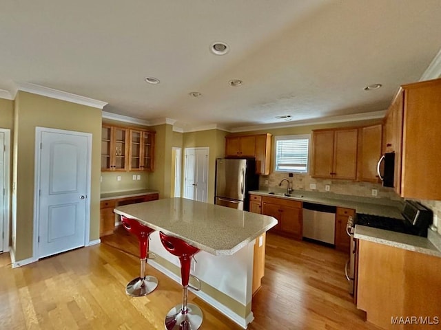 kitchen featuring sink, light hardwood / wood-style flooring, appliances with stainless steel finishes, a kitchen breakfast bar, and a center island