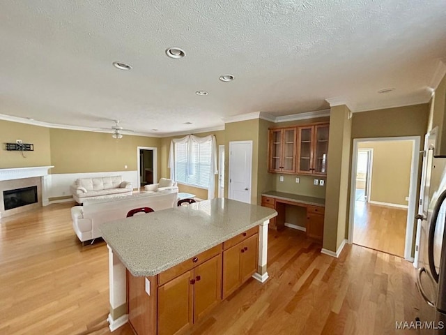 kitchen with built in desk, light wood-type flooring, stainless steel fridge, crown molding, and a textured ceiling