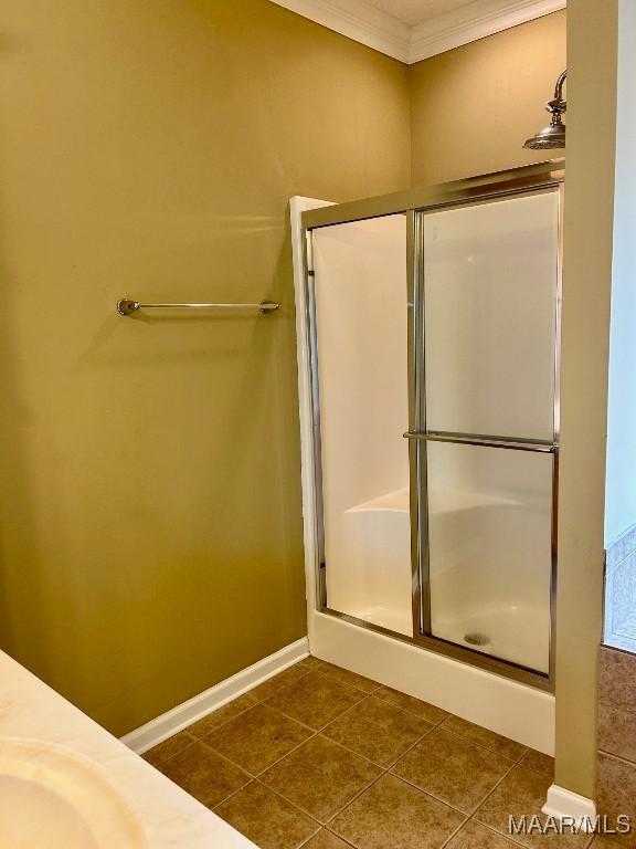 bathroom with tile patterned flooring, crown molding, and a shower with door