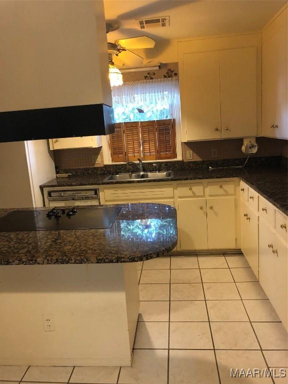 kitchen with white cabinetry, sink, light tile patterned floors, and dark stone counters