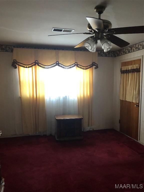 empty room featuring dark carpet and ceiling fan