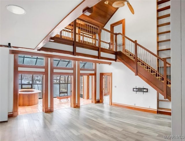 unfurnished living room featuring ceiling fan, high vaulted ceiling, a barn door, and hardwood / wood-style floors