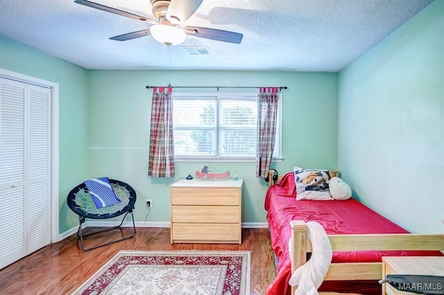 bedroom with ceiling fan, a closet, hardwood / wood-style floors, and a textured ceiling