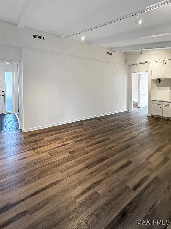 unfurnished living room featuring dark hardwood / wood-style flooring, rail lighting, and beamed ceiling