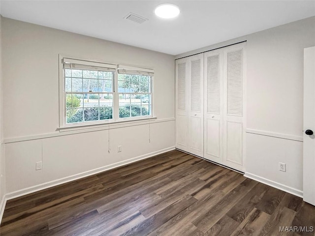 unfurnished bedroom featuring dark wood-type flooring and a closet