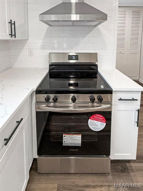 kitchen featuring extractor fan, tasteful backsplash, stainless steel range with electric stovetop, light stone countertops, and white cabinets