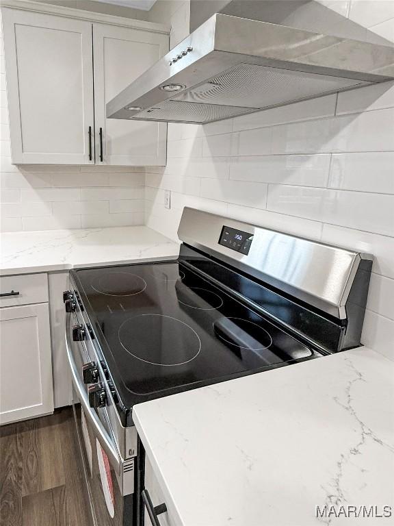 kitchen with white cabinetry, backsplash, electric range, light stone countertops, and exhaust hood