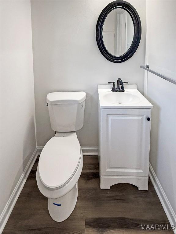 bathroom featuring wood-type flooring, toilet, and vanity