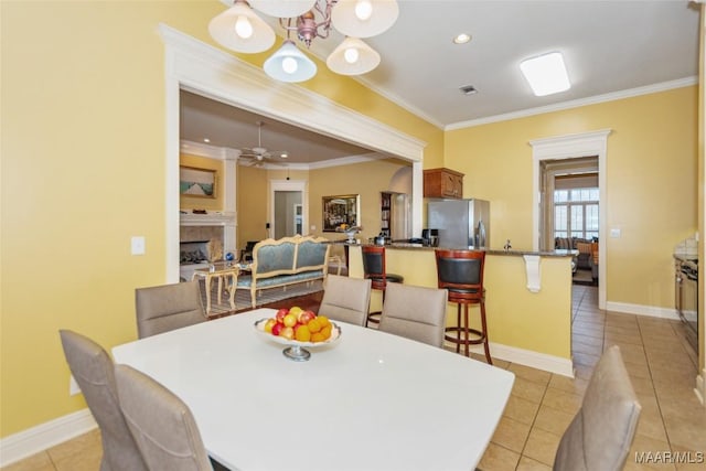 dining space with ornamental molding, light tile patterned floors, and a fireplace