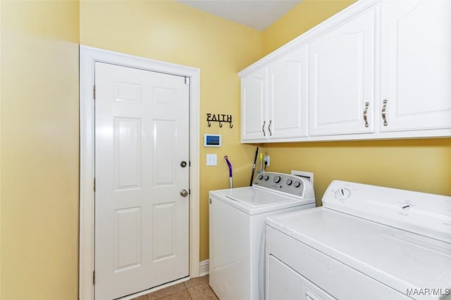 laundry area with cabinets, light tile patterned floors, and washing machine and clothes dryer