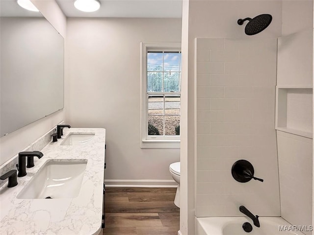 bathroom featuring a sink, toilet, wood finished floors, and  shower combination