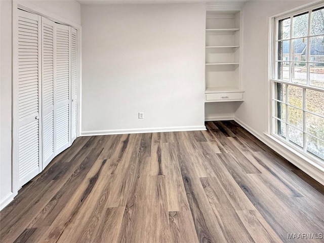 unfurnished bedroom featuring baseboards, a closet, and dark wood finished floors