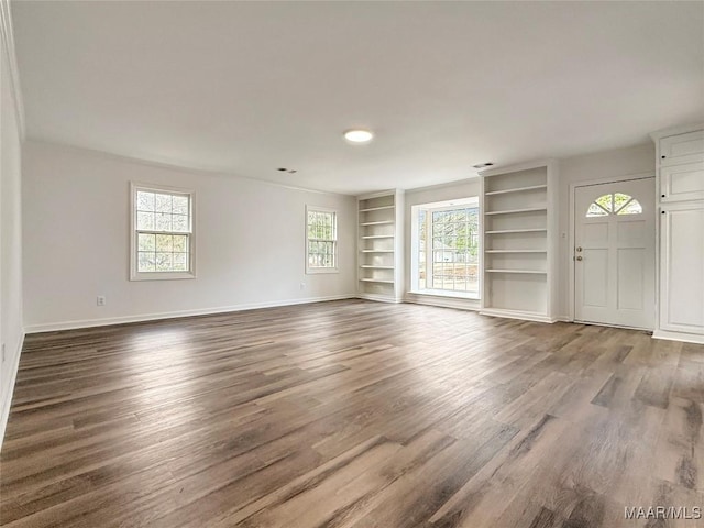 unfurnished living room featuring hardwood / wood-style floors and built in features