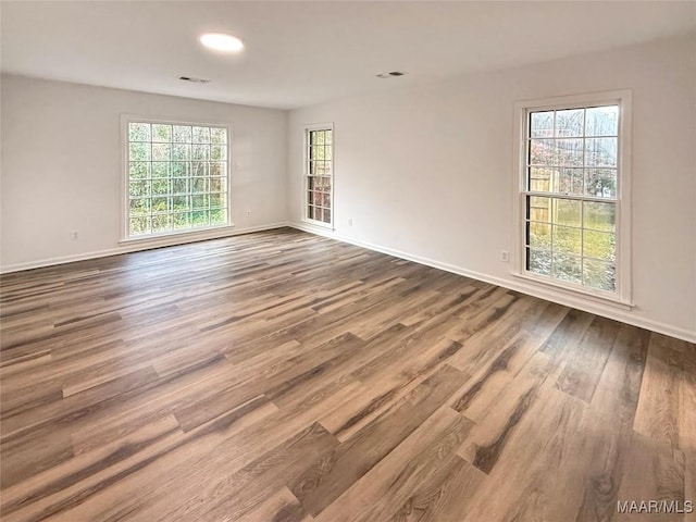 empty room with recessed lighting, baseboards, visible vents, and wood finished floors