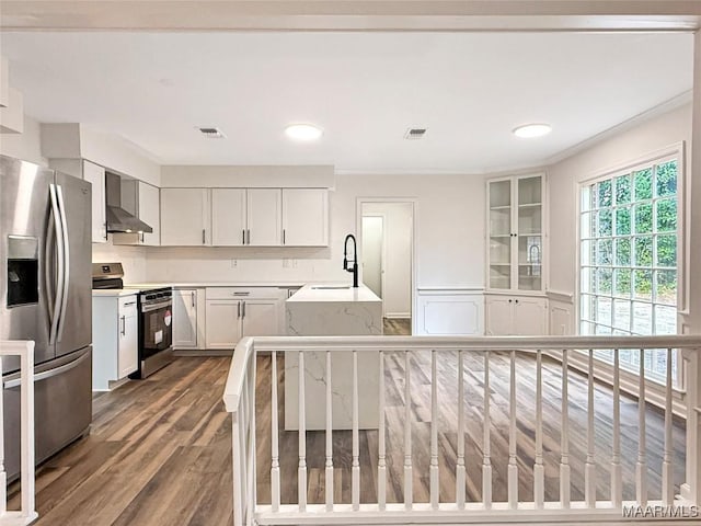 kitchen with white cabinetry, sink, hardwood / wood-style flooring, stainless steel appliances, and wall chimney exhaust hood