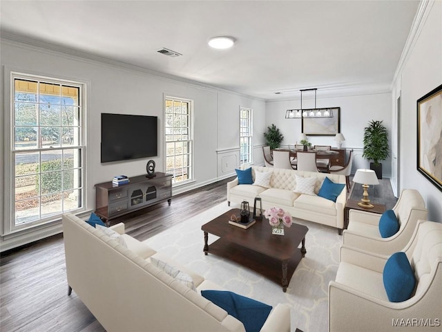living room with plenty of natural light, ornamental molding, wood finished floors, and visible vents