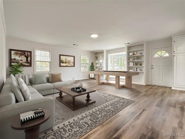 living room featuring built in features, baseboards, and wood finished floors