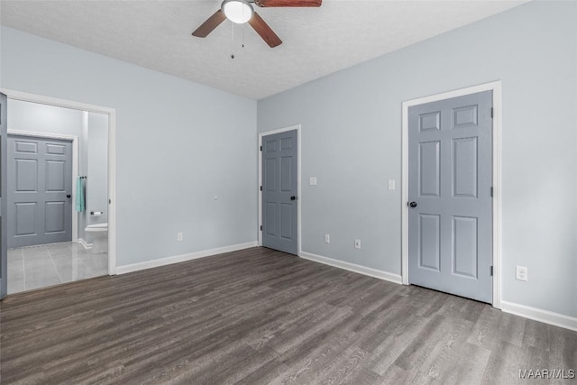 unfurnished bedroom featuring baseboards, wood finished floors, a textured ceiling, and ensuite bathroom