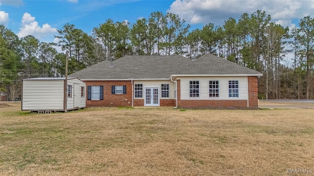 back of house with brick siding, a yard, french doors, and a storage unit