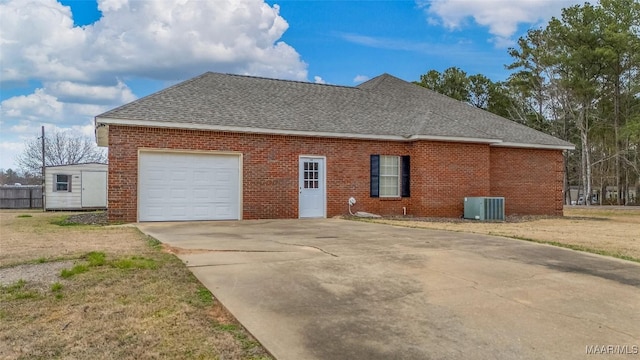 view of side of home with concrete driveway, a shingled roof, an attached garage, cooling unit, and brick siding