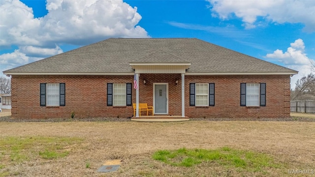ranch-style house with a shingled roof, brick siding, and a front yard