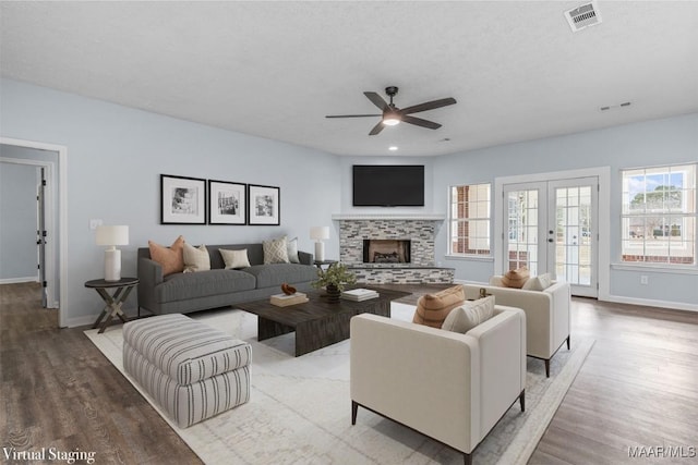 living room featuring a tile fireplace, wood-type flooring, ceiling fan, a textured ceiling, and french doors