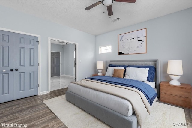 bedroom with ensuite bathroom, dark hardwood / wood-style floors, ceiling fan, and a textured ceiling