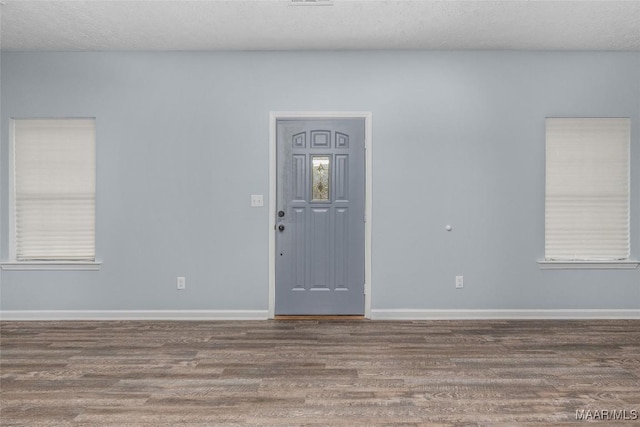 interior space with wood finished floors, a textured ceiling, and baseboards