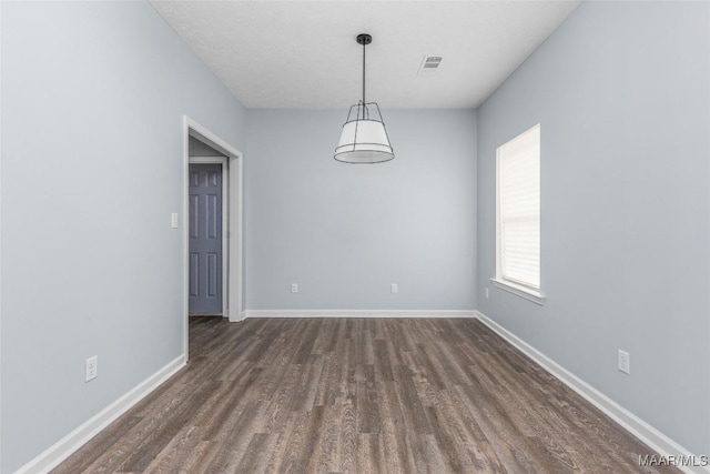 unfurnished room featuring dark wood finished floors, visible vents, and baseboards