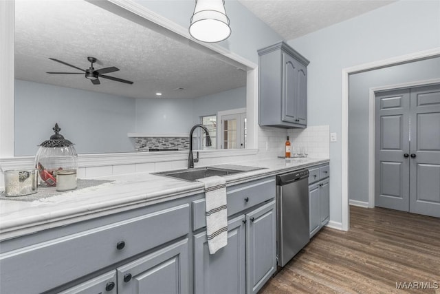 kitchen with sink, gray cabinetry, tasteful backsplash, stainless steel dishwasher, and dark hardwood / wood-style flooring