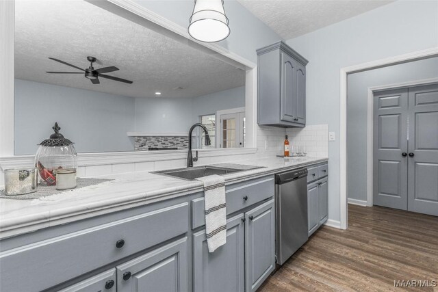 kitchen featuring stainless steel dishwasher, a sink, a textured ceiling, ceiling fan, and gray cabinets