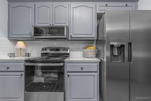 kitchen featuring tasteful backsplash, gray cabinets, and stainless steel appliances