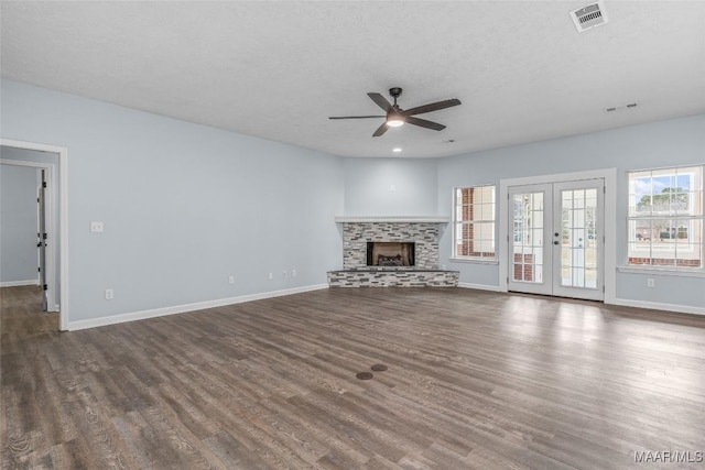 unfurnished living room with a fireplace, ceiling fan, dark wood-type flooring, a textured ceiling, and french doors