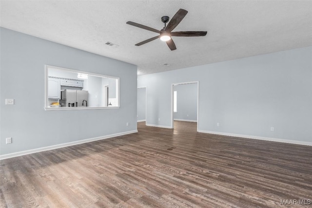 unfurnished living room featuring ceiling fan, hardwood / wood-style flooring, and a textured ceiling