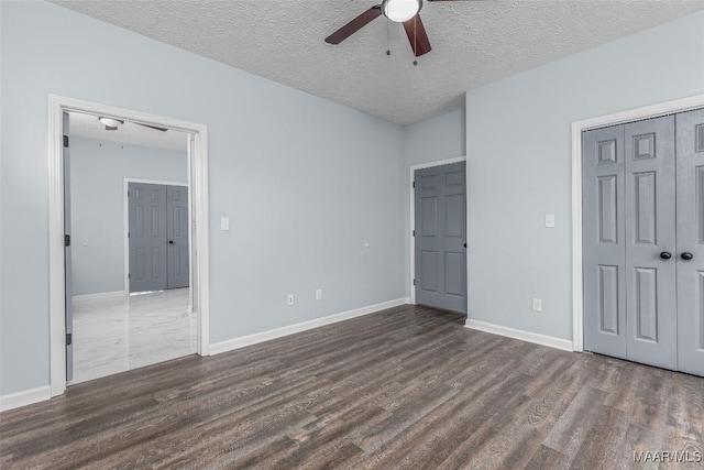 unfurnished bedroom featuring dark wood-type flooring, ceiling fan, a closet, and a textured ceiling