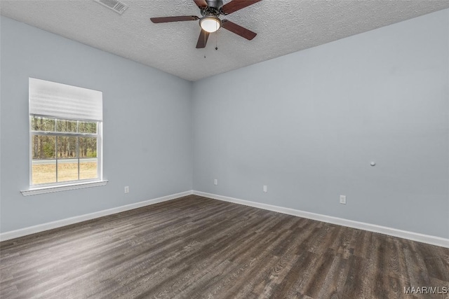 empty room with baseboards, dark wood-type flooring, visible vents, and a textured ceiling