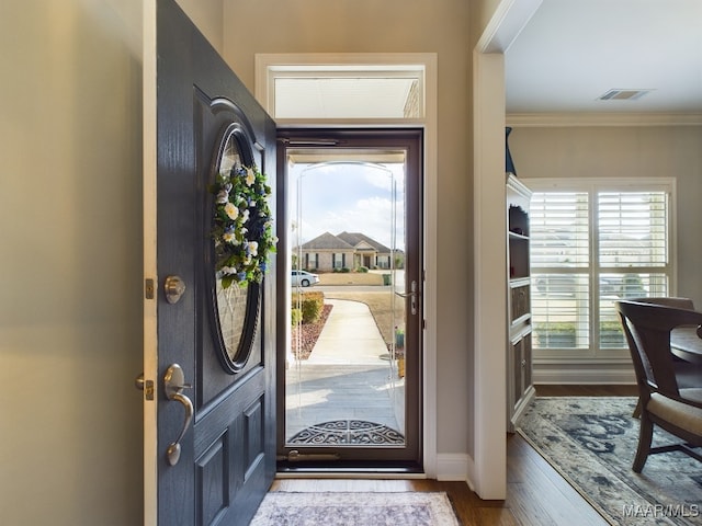 foyer entrance featuring wood-type flooring, a wealth of natural light, and crown molding