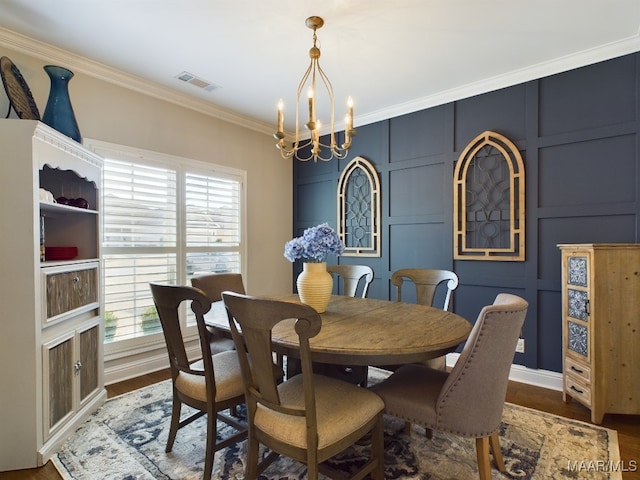 dining area with ornamental molding, wood-type flooring, and a notable chandelier