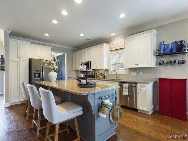 kitchen featuring white cabinetry, stainless steel appliances, light stone countertops, and a kitchen island