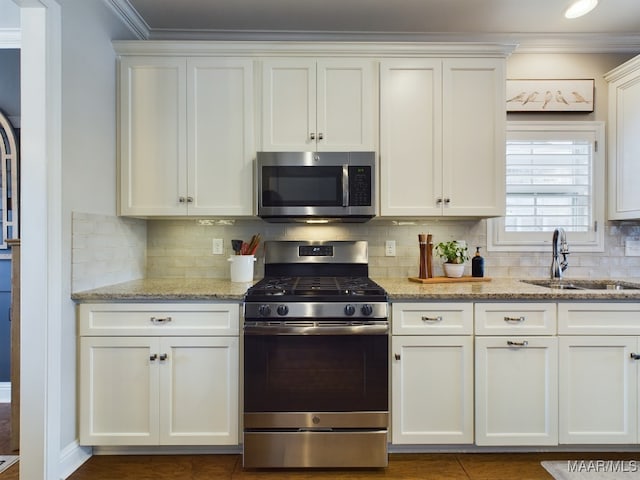 kitchen featuring sink, white cabinets, stainless steel appliances, crown molding, and light stone countertops