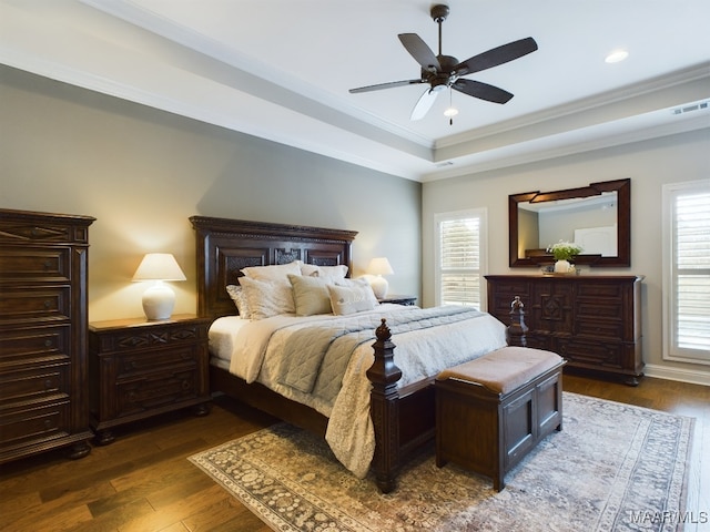 bedroom featuring dark hardwood / wood-style flooring, a tray ceiling, ornamental molding, and ceiling fan