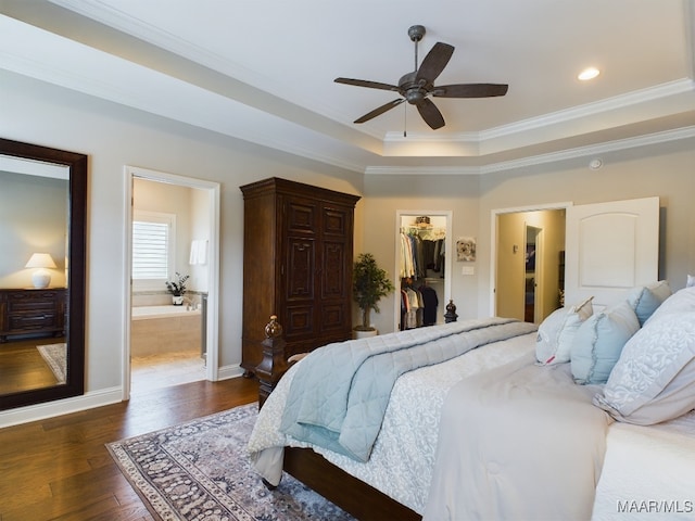 bedroom featuring crown molding, dark hardwood / wood-style floors, a raised ceiling, a walk in closet, and a closet