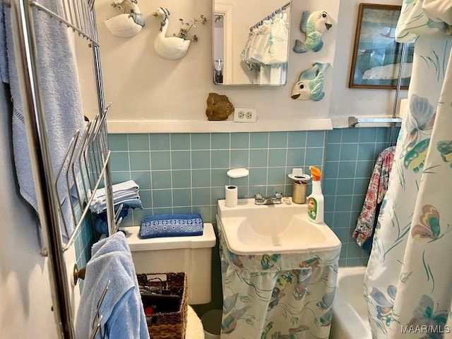 full bathroom featuring toilet, shower / bathtub combination with curtain, sink, and tile walls