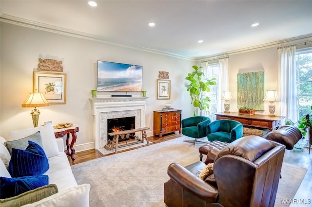 living room featuring crown molding, a high end fireplace, and light hardwood / wood-style flooring