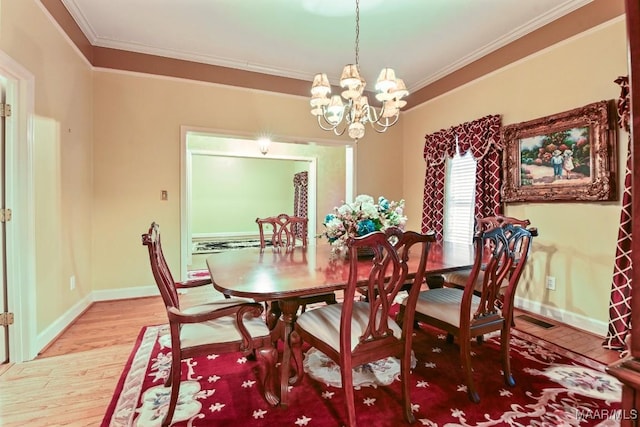 dining space featuring hardwood / wood-style flooring, ornamental molding, and an inviting chandelier